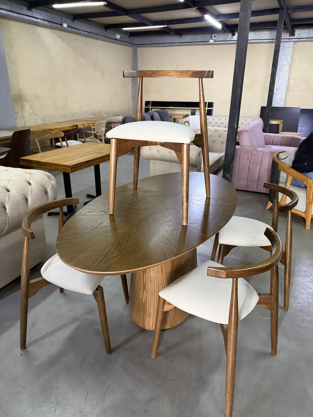 Comedor con mesa oval de pedestal y sillas tipo codo en madera con asiento tapizado