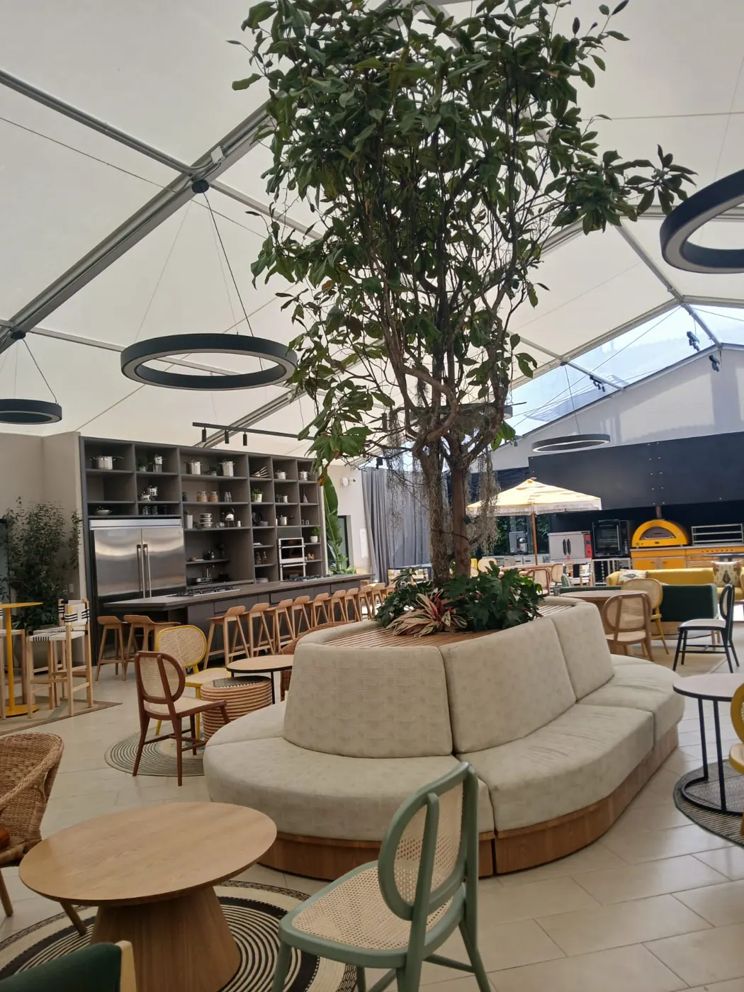 Zona lounge de hospitality con sofá curvo modular fabricado a medida alrededor de jardinera central